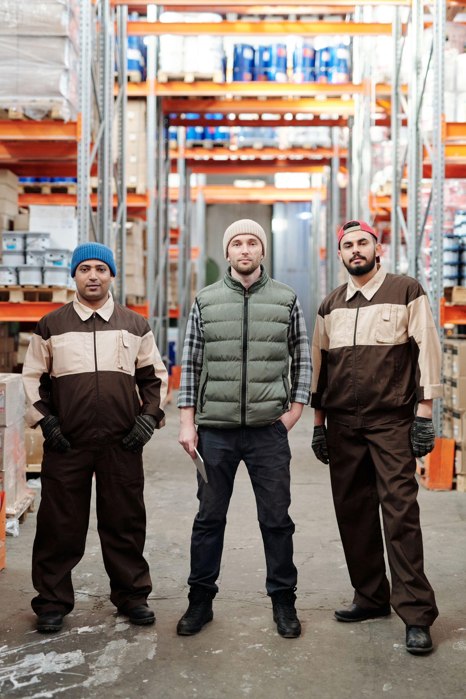 Three warehouse workers in uniform standing in an organized storage area